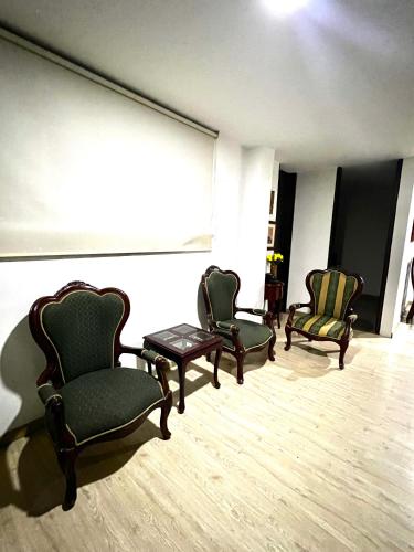 um quarto com três cadeiras, uma mesa e uma janela em Tomasa guest house em Bogotá