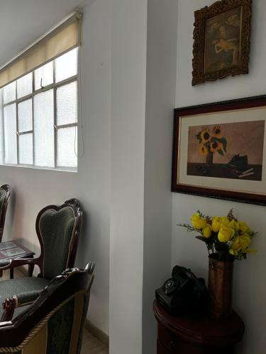 um quarto com cadeiras e um vaso de flores amarelas em Tomasa guest house em Bogotá