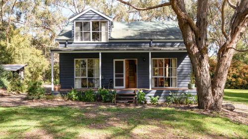 a gray house with a porch and a tree at Ethel - Drummond Park Cottages in Drummond