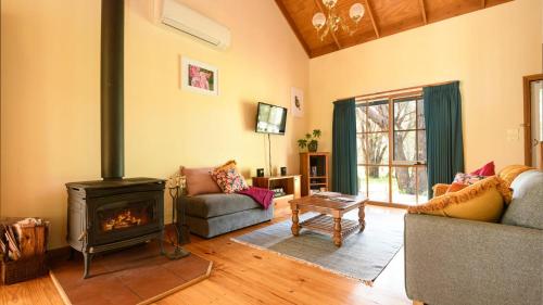 a living room with a fireplace and a couch at Ethel - Drummond Park Cottages in Drummond