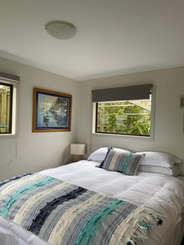 a bedroom with a large bed and two windows at Sea View Apartment in Whangaparaoa