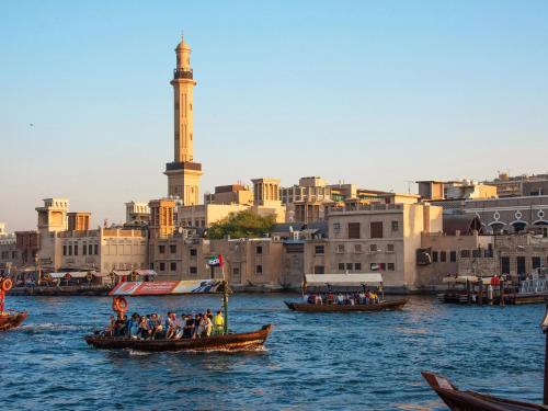 a group of people on gondolas on a river with a city at Flora Inn Hotel Dubai Airport in Dubai