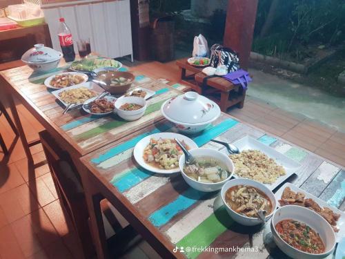 a wooden table with many dishes of food on it at Kedthawa Homestay เฮือนเก็ดถะหวา in Ban Cho Lae