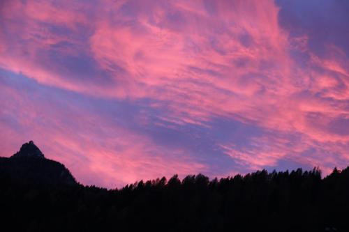 a sunset sky with trees in the foreground at Dolomiti house in Cibiana