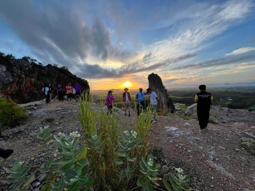 a group of people walking on a mountain at sunset at โฮมสเตย์บ้านนายสิงโตเขาคูหา in Ban Khu Ha Nai (1)