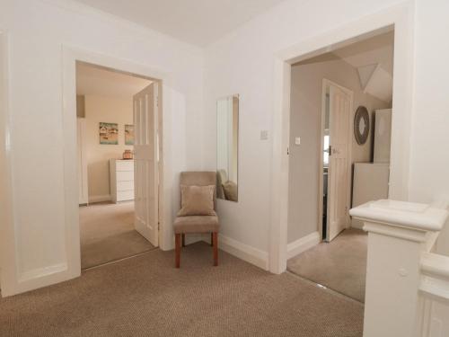 a white room with a chair and a mirror at 2 Moorlands in Minehead