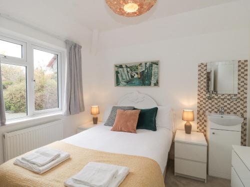 a bedroom with a bed and a sink and two lamps at 2 Moorlands in Minehead