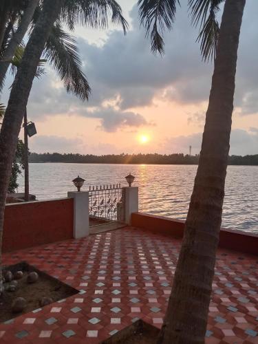un coucher de soleil sur une étendue d'eau avec deux palmiers dans l'établissement Korjai kinara Homestay, à Malvan