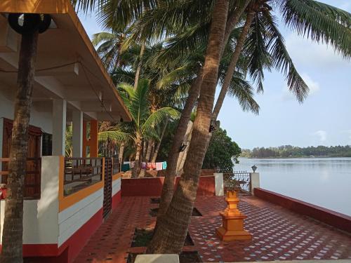 a house with palm trees in front of the water at Korjai kinara Homestay in Malvan