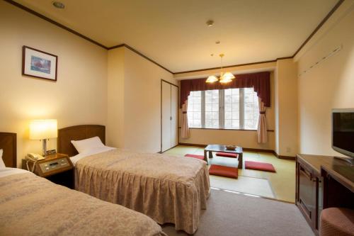 a hotel room with two beds and a television at Hotel Green Plaza Hakuba in Otari