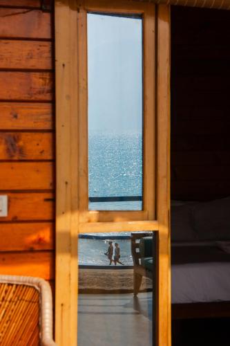 a window in a cabin with a view of the ocean at New Common Home in Agonda