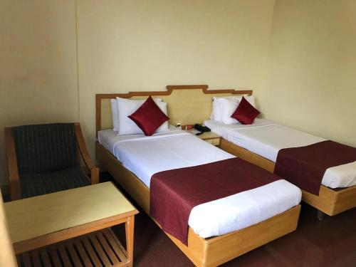 a hotel room with two beds and a chair at Presidency Towers,Kochi in Cochin