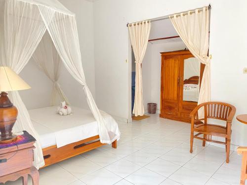 a bedroom with a canopy bed and a chair at suris bungalow 2 in Pabean Buleleng