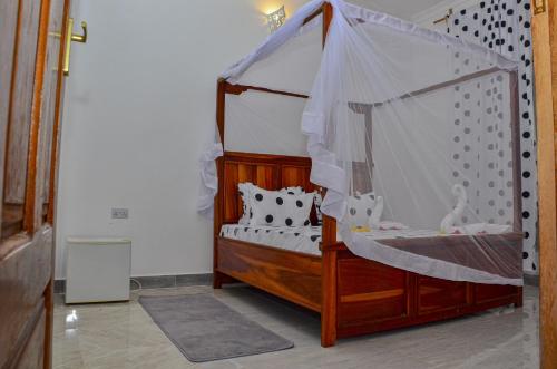 Cette chambre comprend un lit à baldaquin. dans l'établissement Nyota Apartment, à Nungwi