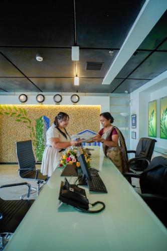 two women sitting at a table with a laptop at Hotel Olive Eva in Kakkanad