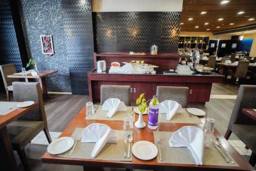 a dining room with a table with plates and napkins at Hotel Olive Eva in Kakkanad