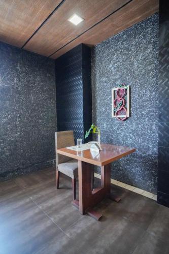 a wooden table with a chair and a painting on a wall at Hotel Olive Eva in Kakkanad