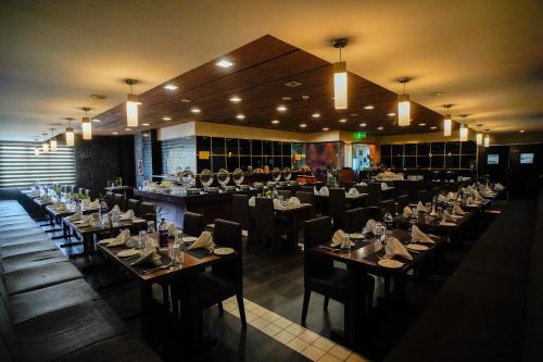 a dining room with tables and chairs and lights at Hotel Olive Eva in Kakkanad