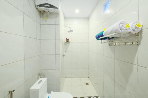 a white bathroom with a toilet and a shower at Green Bali Guest House in Munggu