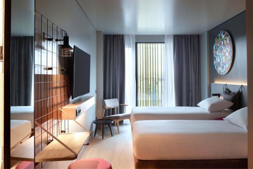 una camera d'albergo con due letti e una televisione di Moxy Athens City ad Atene