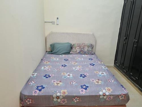 1 cama con edredón púrpura y almohadas en Budget Hostel Rooms, en Al Ain