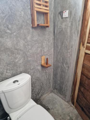 a bathroom with a white toilet in a room at Coconut Mafia Island Bungalows in Utende