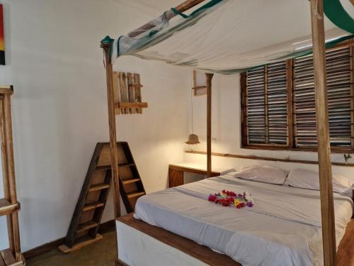 een slaapkamer met een bed met een ladder en bloemen erop bij Mafia Island Bungalows in Utende