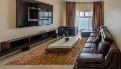 a living room with a leather couch and a tv at Dibba Sea View Hotel by AMA Pro in Dibba