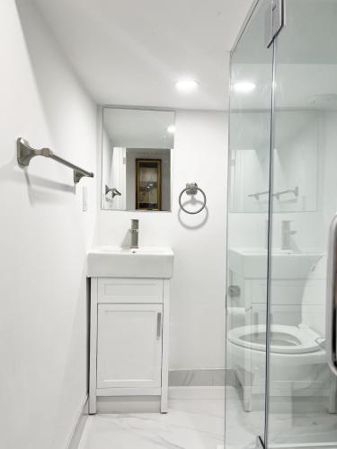 a white bathroom with a sink and a toilet at Tidy Private Rooms with Full Kitchen in Toronto