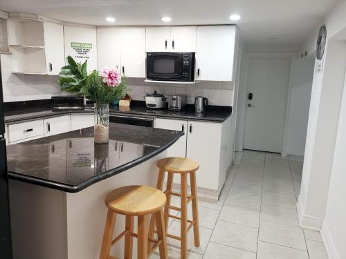 een keuken met een aanrecht en 2 krukken bij Tidy Private Rooms with Full Kitchen in Toronto