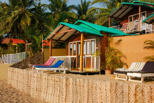 una casa sulla spiaggia con sedie e ombrelloni di New Common Home ad Agonda