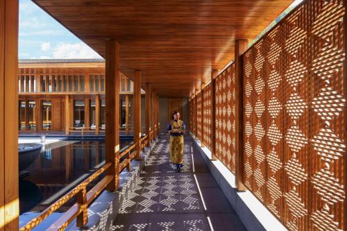 a woman walking down a corridor in a building with a pool at Vivanta Tawang in Tawang