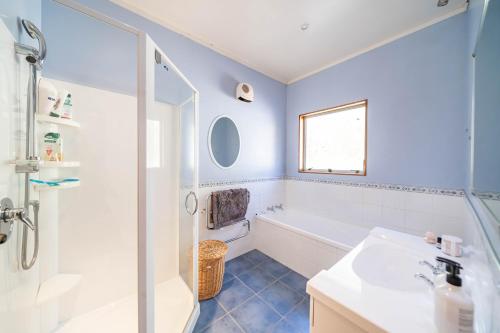 een badkamer met een bad, een wastafel en een douche bij Eclectic Luxurious 70s Mansion in Wellington