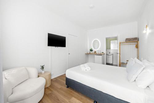 a white room with a bed and a couch and a tv at Central Motel Mooloolaba and Apartments in Mooloolaba