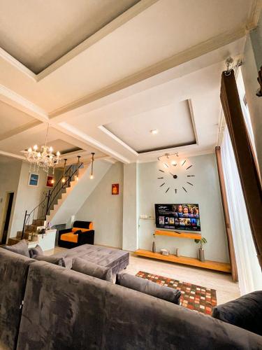 a living room with a large couch and a clock on the wall at Villa Kamar Tamu Warungboto in Yogyakarta