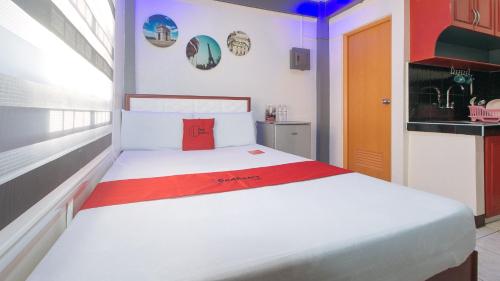 1 dormitorio con cama blanca y almohada roja en RedDoorz A&F C5 Pinagsama Taguig en Manila