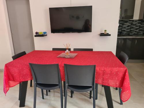 a dining room table with a red tablecloth and black chairs at L appart du trou d eau in La Saline les Bains