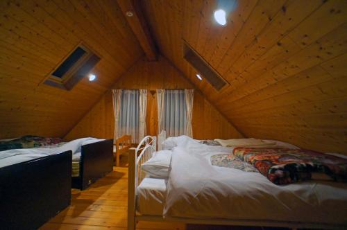 a room with two beds in a wooden cabin at HARUNA LODGE Private log house with starry sky from the skylight, fireplace, and spacious deck BBQ in Nasu