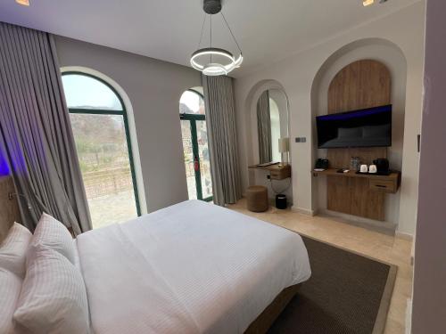 a bedroom with a white bed and a flat screen tv at Dibba Mountain Park Resort in Fujairah