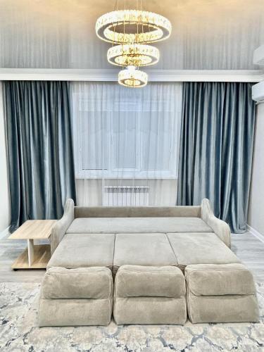 a bedroom with a large bed and a chandelier at # 67 Привлекательная и просторная студия in Atyraū