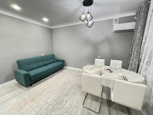 a living room with a table and a green couch at # 67 Привлекательная и просторная студия in Atyraū