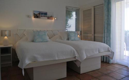 a bedroom with a white bed with blue pillows at Saint Barth Villa 7 in Pointe Milou