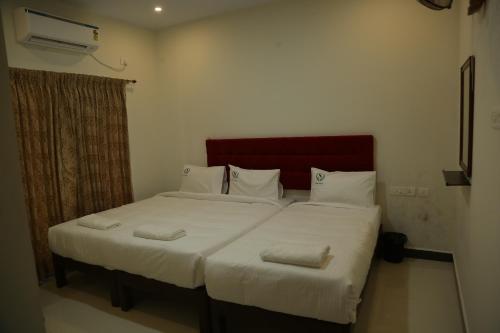a bedroom with a bed with white sheets and pillows at HOTEL TAWFEEQ PALACE in Thanjāvūr