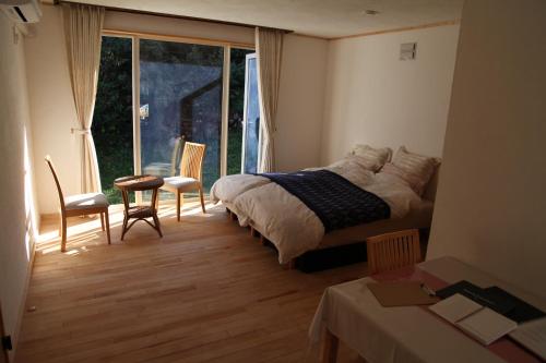 Nishi-kagura的住宿－西神楽の杜，一间卧室配有一张床、一张桌子和一个窗户。