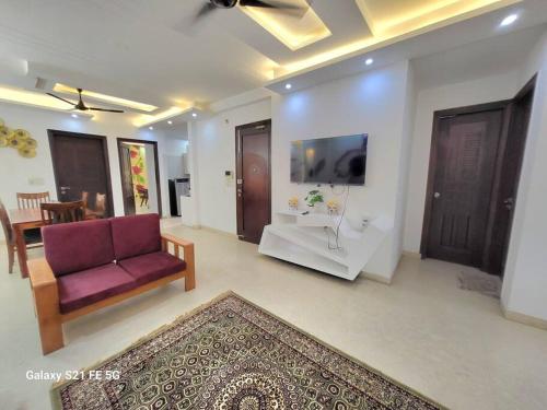 a living room with a couch and a tv at BnBBuddy Athulyam 3 BHK Homestay, Shalimar Bagh in New Delhi