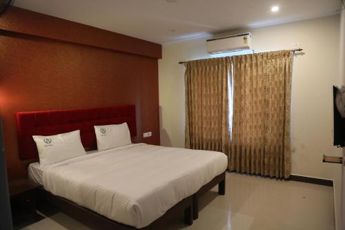 a bedroom with a bed with a red headboard and a window at HOTEL TAWFEEQ PALACE in Thanjāvūr