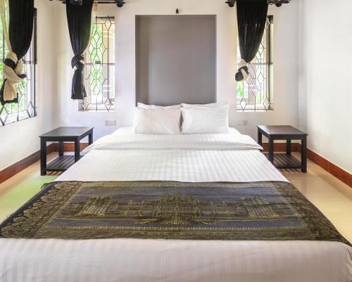 a bedroom with a large white bed with two tables at Le petit nid Banana resort in Phumĭ Réach Born