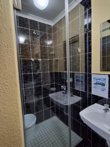 uma casa de banho com um chuveiro, um WC e um lavatório. em Old Oak Guest House em Bellville