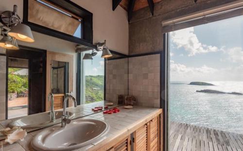 a bathroom with a sink and a view of the ocean at Saint Barth Villa 8 in Pointe Milou