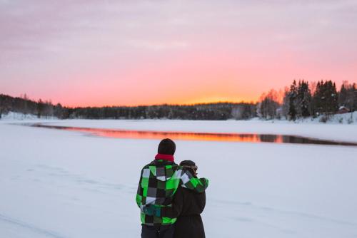 a man taking a picture of the sunset in the snow at Kalix Riverside inn in Kalix